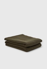 Coperta testurizzata verde scuro, piegata in modo ordinato e mostrata, realizzata in tessuto morbido con un motivo intrecciato.