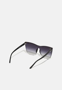 Ochelari de soare tip cat-eye negri cu lentile gri degradate, design elegant și brațe subțiri. Are brandul "QUAY" pe lateral.