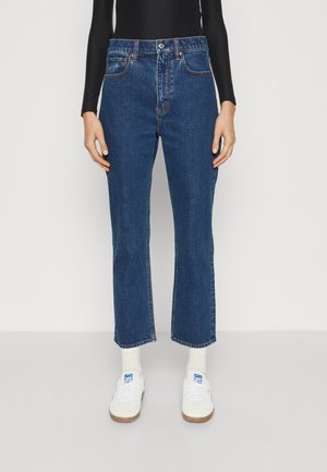 High-waisted blue denim jeans with a straight-leg fit, featuring classic five-pocket design and contrast stitching. Paired with white sneakers.