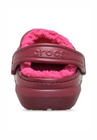 Crocs Clogs in dunklem Burgunderrot mit einem fuzzy pinken Futter und verstellbarem Rückenriemen. Verfügt über eine strukturierte Sohle für Grip und Komfort.