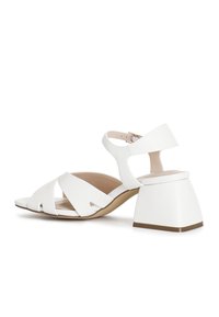 Witte hiel-sandalen met een flinke hak, open teen en crisscross bandontwerp. Gemaakt van soepel materiaal met een neutrale binnenzool.