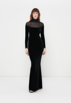 Black velvet long-sleeve gown with a sheer neck and upper bodice. Fitted silhouette flares at the bottom. Simple silver bracelet accents.