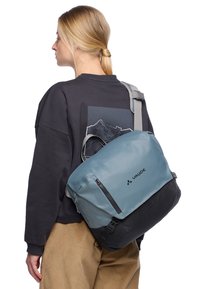 Borsa a tracolla Vaude blu e nera con una texture liscia, ampio scomparto con zip e tracolla regolabile.