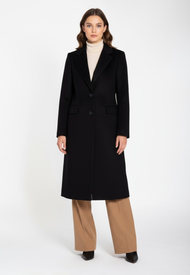 Long black wool coat with a tailored design, notched lapels, two buttons, and side pockets, worn over a beige turtleneck and beige trousers.