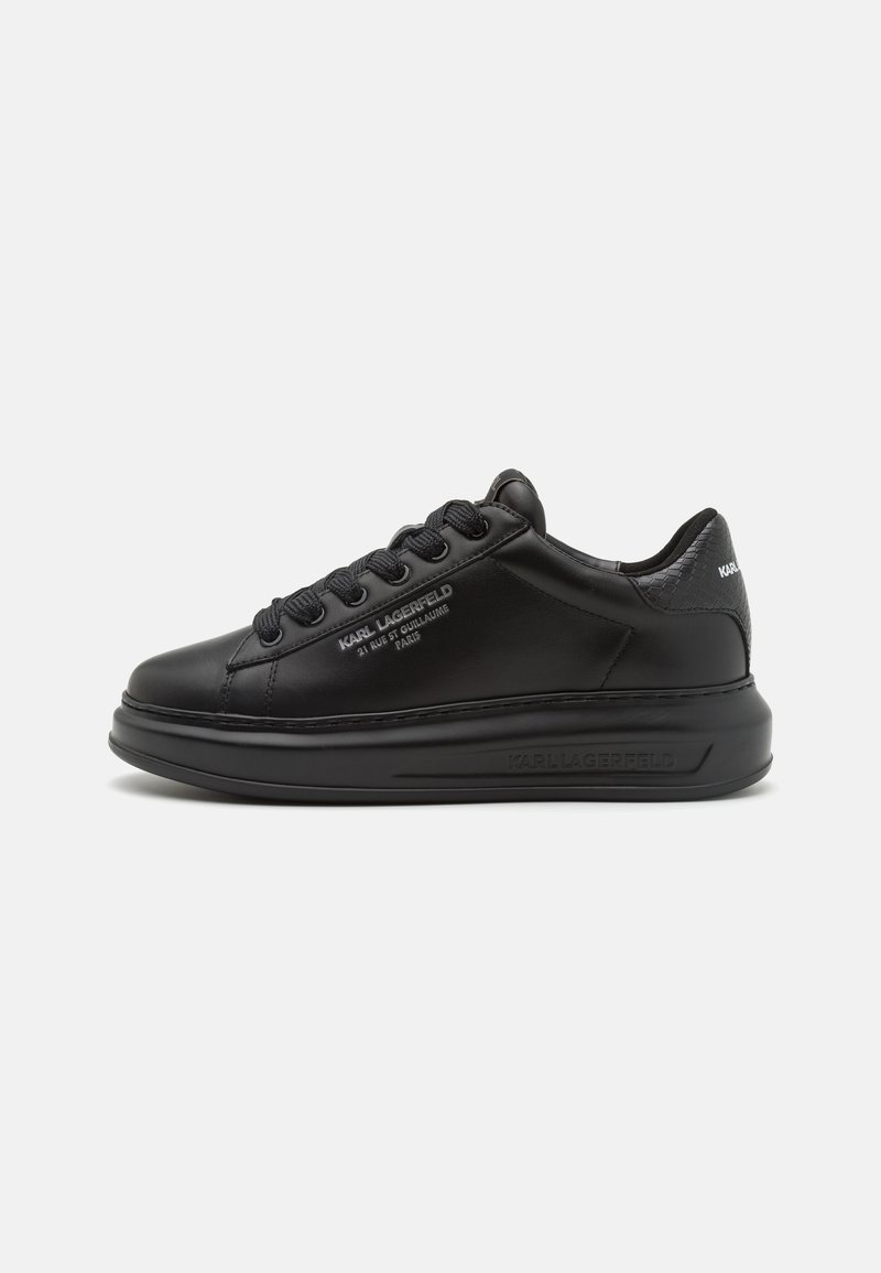 Sneaker in pelle nera con punta arrotondata, suola spessa e testurizzata, lacci piatti e dettaglio del marchio stampato sul lato e sul tallone.