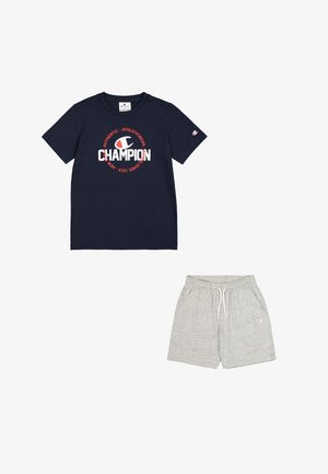 Camiseta navy con el logotipo "Champion" en rojo y blanco, combinada con pantalones cortos grises con cinturilla elástica y bolsillos. Mezcla de algodón, corte casual.