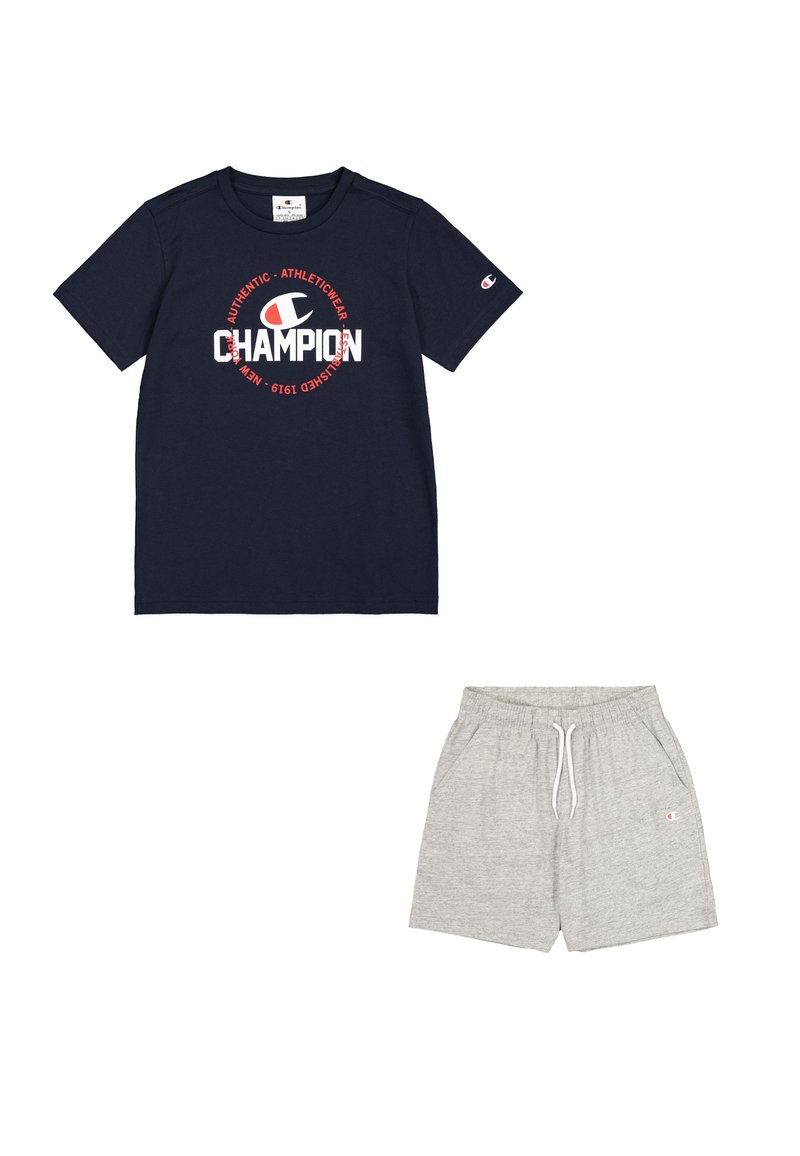 Camiseta navy con el logotipo "Champion" en rojo y blanco, combinada con pantalones cortos grises con cinturilla elástica y bolsillos. Mezcla de algodón, corte casual.