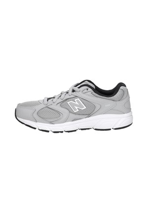 Grijze en witte New Balance hardloopschoen met meshpanelen, "N" logo aan de zijkant en zwarte binnenvoering, gezien vanaf de buitenkant.