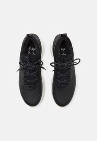 Black athletic sneakers with a textured upper, tied laces, and a cushioned white sole. Features logo detail on the side and tongue.