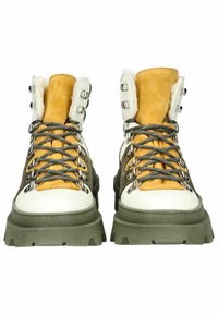 Scarpe da trekking marroni e gialle con suole bianche, materiali in suede e pelle, occhielli metallici per i lacci e suole robuste e texturizzate.