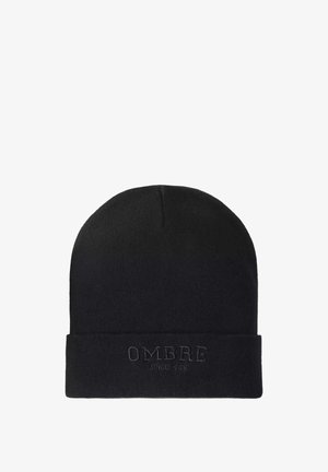 Black knitted beanie hat featuring a rolled cuff with embossed "OMBRE" and "SINCE 1985" text. Soft texture and close-fitting design.