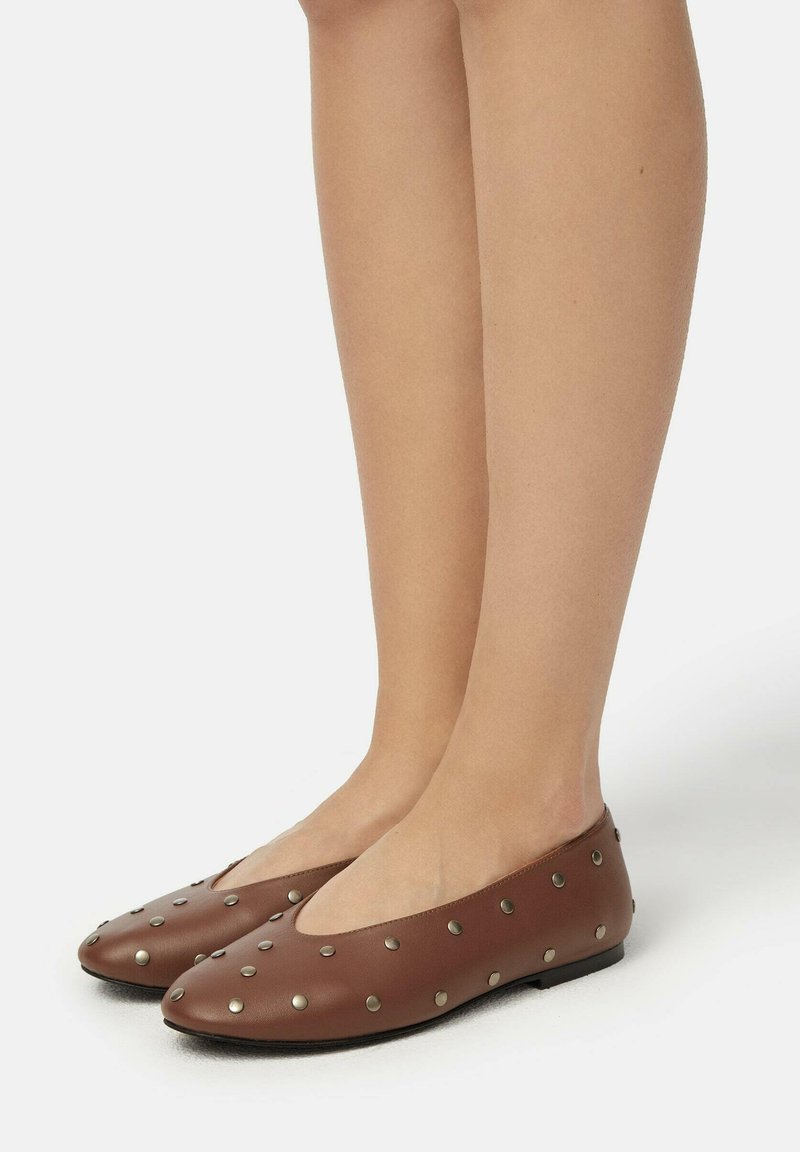 Bruine leren ballerina's met een ronde neus, voorzien van metalen studs die gelijkmatig over het oppervlak zijn verspreid. De schoenen hebben een lage profiel en een platte zool.
