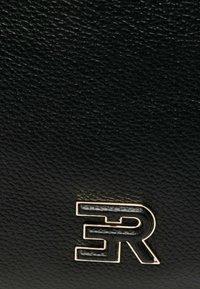 Sac en cuir noir texturé avec un logo en métal doré. La surface présente une finition granuleuse, mettant en valeur ses détails de design élégants.