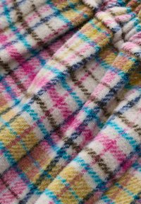 Tkanina wełniana w intensywnym wzorze tartan z różowymi, niebieskimi i żółtymi kwadratami oraz paskami na kremowym tle. Miękka tekstura.