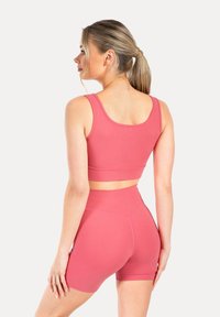 Różowa top sportowy i szorty w kolorze malinowym, wykonane z gładkiego, elastycznego materiału. Charakteryzują się dopasowanym krojem, szerokimi ramiączkami oraz wysokim stanem.