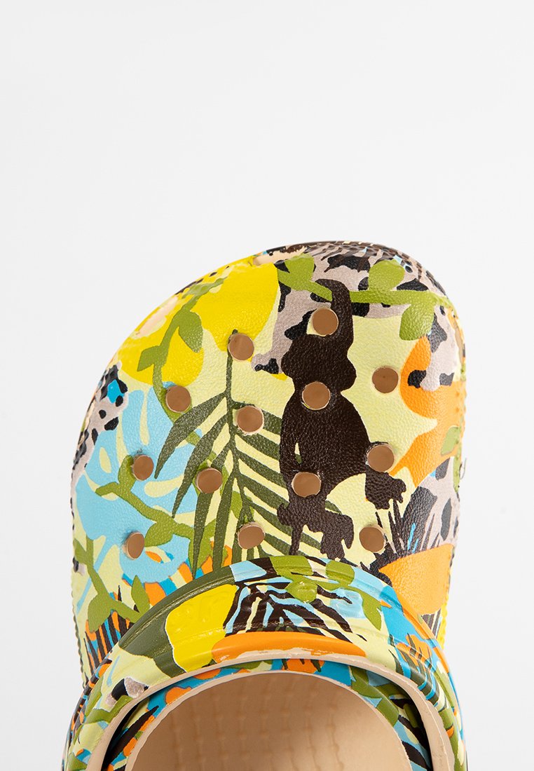 Zuecos con patrones de flores en colores vibrantes, que presentan acentos en amarillo, azul, verde y marrón, con remaches dorados y superficies texturizadas.