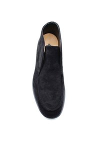 Chaussure slip-on en suède noir avec une texture lisse, bout arrondi et coutures minimales. Semelle plate avec un léger éclat.