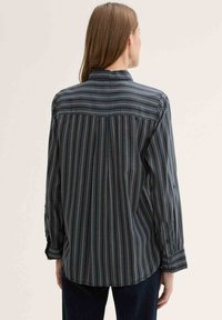 Long-sleeve shirt with a dark striped pattern, featuring a button-down collar, textured fabric, and buttoned cuffs. Back view shown.