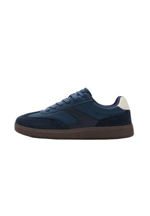Dark blue low-top sneaker with lace-up front, textured brown sole, and white heel patch, shown from the inner side on a white background.