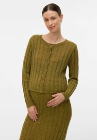 Grön ribbad stickad cardigan med rund halsringning, framknappar och långa ärmar, i kombination med en matchande kjol. Mjuk textur och strukturerad design.