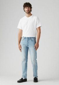 Jean de color azul claro y una camiseta blanca lisa. Los jeans tienen un corte recto y un acabado deslavado, mientras que la camiseta es de manga corta y suave.