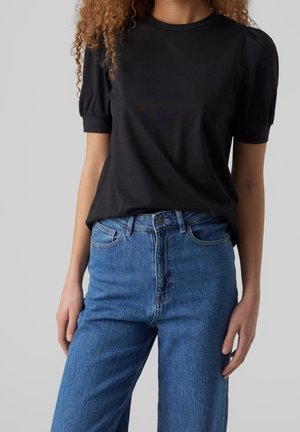 Black short-sleeve top with puffed shoulders, paired with high-waisted blue jeans featuring a classic five-pocket design and a slightly relaxed fit.
