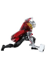 Kristallfigur av en karaktär i en röd och svart mantel, kromad silverkropp, med en silvrig hammare, i knästående pose, detaljerad skulpturering.