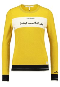 Żółty sweter z dzianiny z białą poziomą linią z tekstem "Entrée des Artistes." Czarne ściągacze przy rękawach i dolnej krawędzi oraz metka z logo.