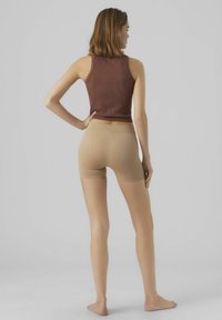 Top in cotone marrone a costine e pantaloni bike in nude, entrambi aderenti. Texture lisce, con un design semplice, adatti per un abbigliamento casual.