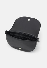 Sac à main noir en cuir avec un rabat arrondi, quincaillerie en argent et une poche intérieure zippée pour l'organisation. Finition texturée.