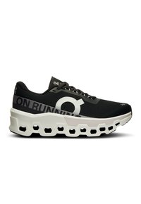 Scarpe da corsa imbottite in bianco e nero con suola a motivo esagonale e testo "ON RUNNING" sul lato.