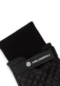 Črne usnjene rokavice s quilted vzorcem, ki imajo rebrast črn tekstilni zapestni del in gumb za zapiranje z logotipom "KARL LAGERFELD".