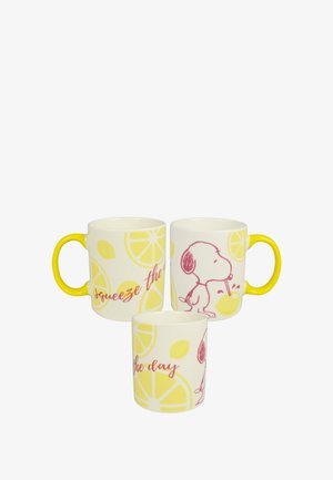 Tazze di ceramica con manici gialli, decorate con motivi di limoni e illustrazioni rosa di un cane che beve succo di limone. Il testo recita "Cogli l'attimo."