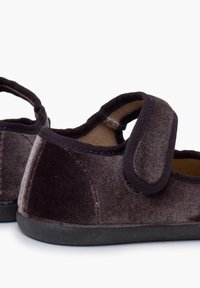 Pantofole in velluto grigio scuro con una texture morbida, caratterizzate da una chiusura con cinturino nero e una suola nera robusta. Rifinite con profili coordinati.