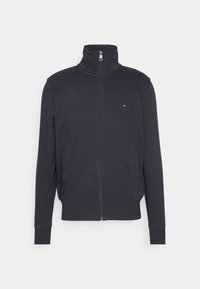 Giacca in pile nera con zip, colletto alto e tasche laterali, mostrata su uno sfondo chiaro uniforme.