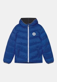 Blå puffjacka med huva, vit dragkedja, elastiska ärmslut och en logopatch på bröstet. Har horisontell quiltad design och dolda fickor.