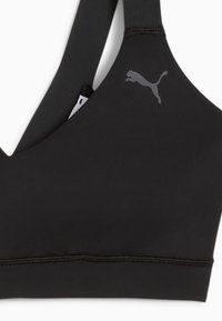 Top sportivo nero con scollatura a V, realizzato in materiale elastico. Presenta spalline sottili e un logo grigio discreto sulla parte superiore sinistra.