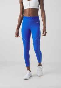 Nike Pro Leggings in Verlaufblau, mit hohem Taillenbund und blauer Schrift, verbindenden Nähten und glattem, dehnbarem Stoff.