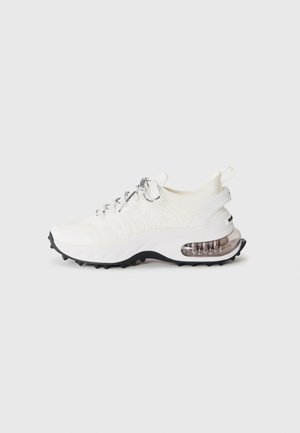 White athletic sneaker with black-tipped laces, textured knit upper, thick sole, visible air cushion in heel, and black tread sole.