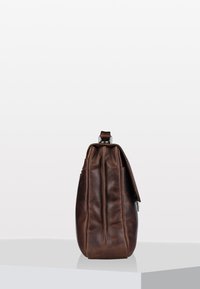 Brown leather bag with smooth texture, rounded shape, and a fold-over flap. Includes a silver hardware accent at the top.