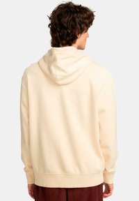 Sudadera color crema con capucha ajustable, puños y dobladillo de canalé, con un corte holgado y textura suave. Diseño minimalista sin patrones.
