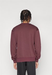 Bordeaux sweatshirt met lange mouwen, ronde hals, ribbelmanchetten en zoom. Gladde textuur met een relaxed fit en geen zichtbare logo's of patronen.