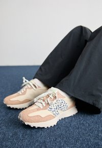 Sneaker in einem pink-beigen Farbschema, mit einem Leopardenmuster-Panel, weißen Schnürsenkeln und strukturierten Wildleder-Akzenten.