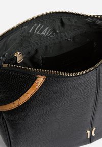 Borsa in pelle nera con superficie testurizzata, cerniera dorata e dettaglio in sughero. L'interno presenta un compartimento con cerniera e una fodera decorata.