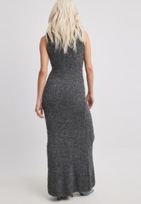 Grå ribbad maxiklänning med en figursydd silhuett och ärmlös design, med en utställd nederkant och texturerad tyg.