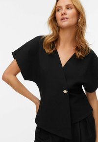 Czarna bluzka typu wrap z krótkimi rękawami, z głębokim dekoltem w kształcie V i dekoracyjnym złotym guzikiem. Gładka tkanina i nowoczesny design.