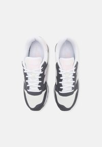 Baskets de sport noir et blanc avec des accents roses, dotées d'une tige en mesh, d'un col rembourré et d'un système de laçage. Marquage "NB 500" sur la languette.