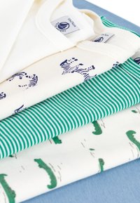 Fire fire topp med korte ermer stablet: kremfarget med svart zebra mønster, hvit med grønne former, grønn-og-hvit stripe, og ensfarget lys blå.