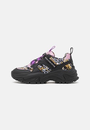 Massiver schwarzer Sneaker mit lila Akzenten, verziertem gold-weißem Barockmuster, dicker Profilsohle und "Versace Jeans Couture"-Branding an der Seite.