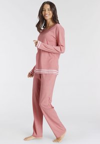 Rosa Loungewear-Set mit langärmeliger Oberteil und passenden Hose. Das Oberteil hat einen runden Halsausschnitt und gestreifte Bündchen. Weicher, strukturierter Stoff.
